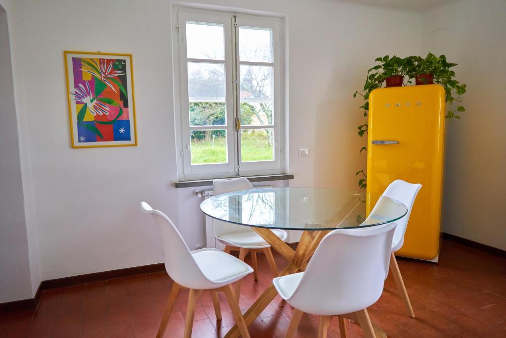 jadalnia ze szklanym stołem i białymi krzesłami w obiekcie AceroRosso Farmhouse w mieście Sarzana