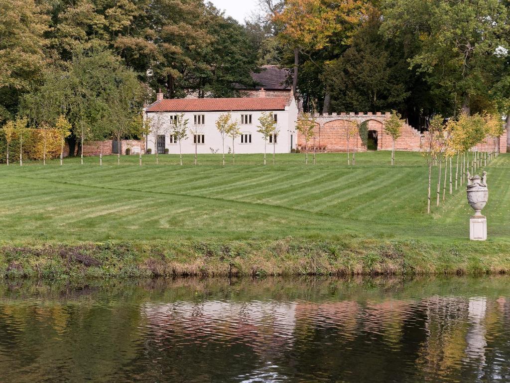 a house by the water with a lawn and a building at Hall Cottage in Brampton