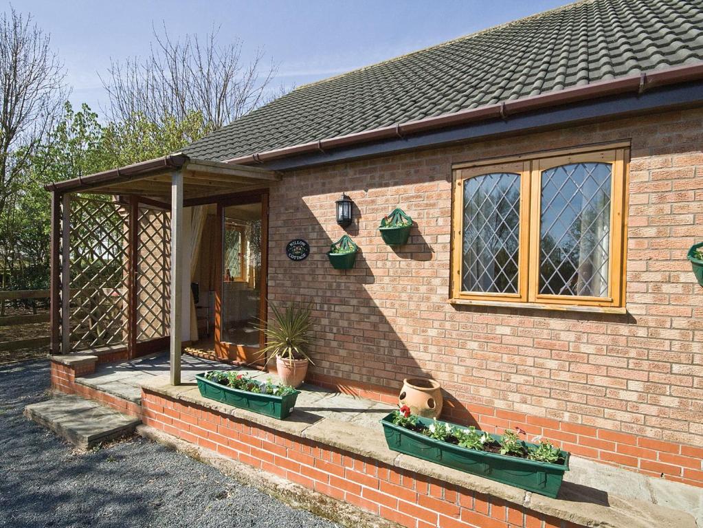 a brick house with two potted plants on the porch at Willow Cottage - E4778 in Atwick