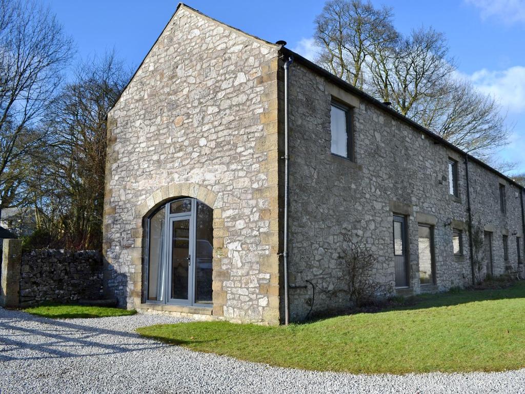 an old stone building with a large door at Barn End Cottage in Millers Dale