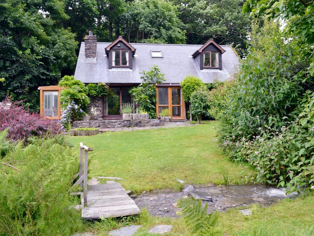a small house with a garden and a wooden bridge at Erw Goed Hen Feudy in Arthog