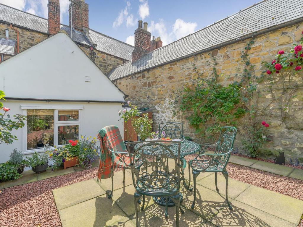 een patio met een tafel en stoelen voor een gebouw bij Harrys Den in Alnwick