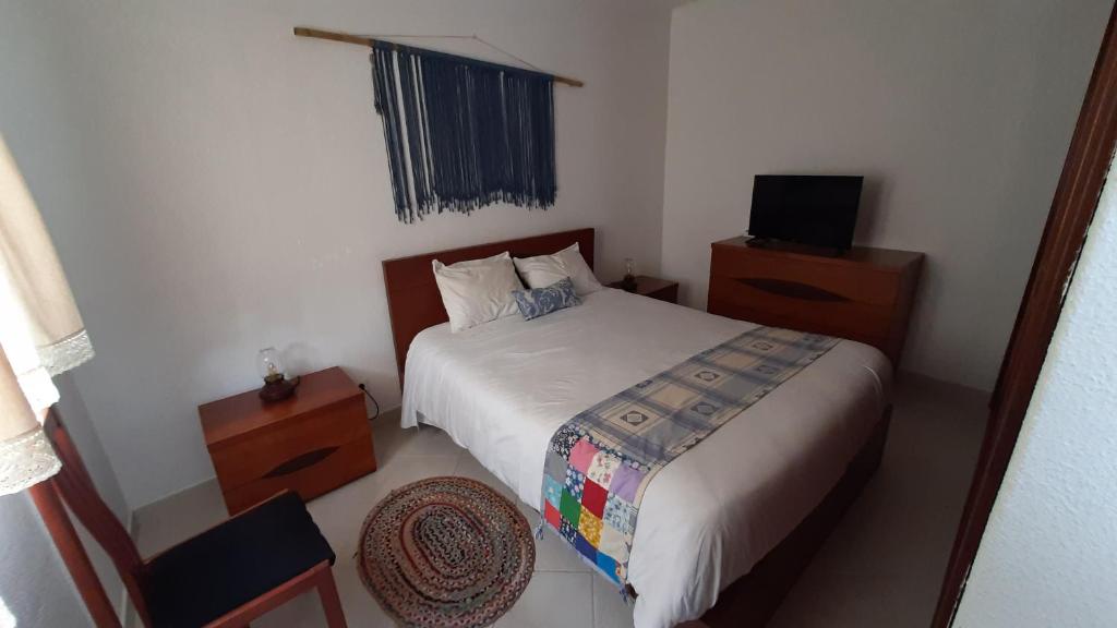 een kleine slaapkamer met een bed en een televisie bij Casinha do Rui in Sines