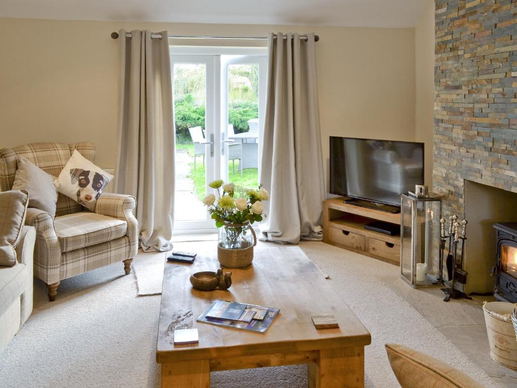 a living room with a couch and a tv at Willow Tree Cottage in Foxholes