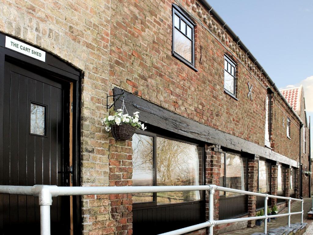 um edifício de tijolos com uma porta e um vaso de plantas em The Cart Shed em Tickton