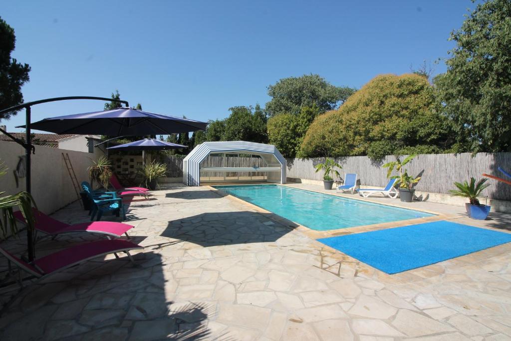 a swimming pool with chairs and an umbrella at Le Jardin du Somail in Le Somail