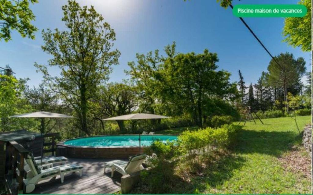 una piscina en un patio con sombrillas en Le mas du goio, en Seillans