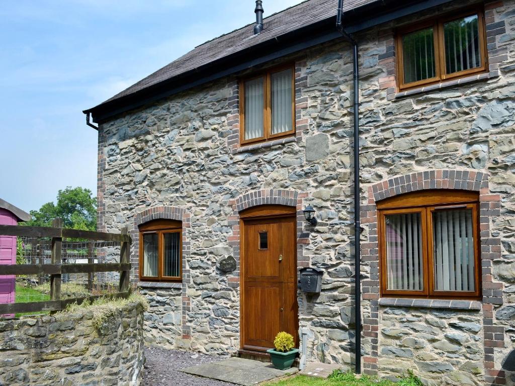 uma casa de pedra com uma porta de madeira e janelas em Bwthyn Clyd em Llangollen