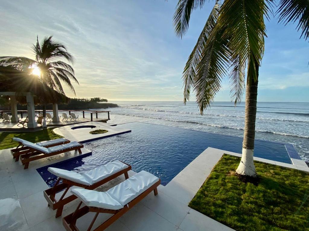 a pool with chairs and a view of the ocean at Vista Las Olas Resort in El Cuco