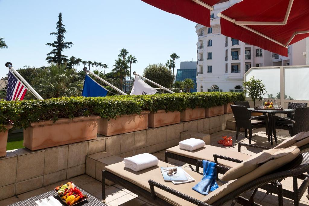 a patio with tables and chairs on a balcony at Hôtel Barrière Le Majestic Cannes in Cannes