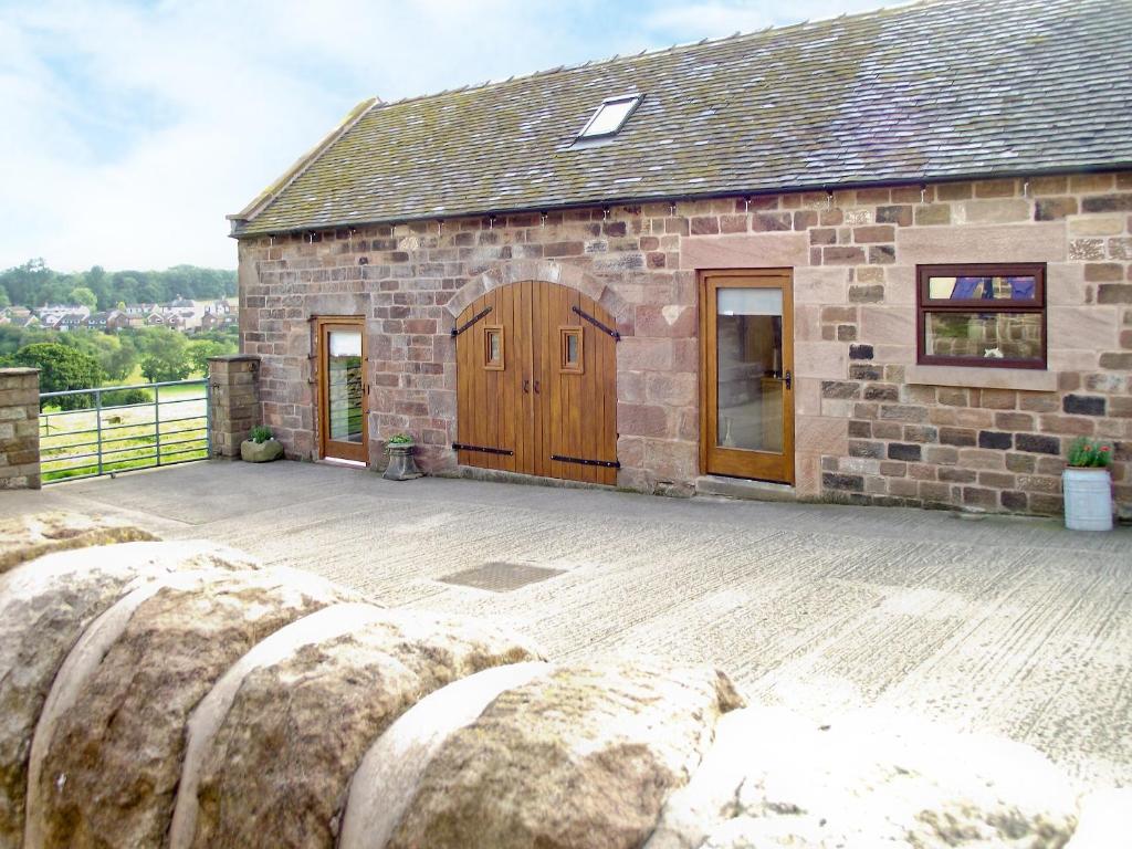 a stone building with a wooden door and a patio at Roaches View Barn in Wetleyrocks