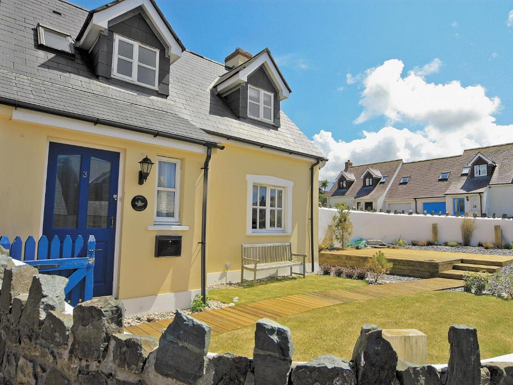 a yellow house with a blue door and a yard at Pebble Cottage - Hw7447 in Broad Haven