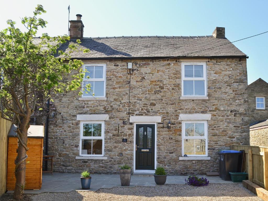 a brick house with white windows at Mill Stone Cottage in Wolsingham