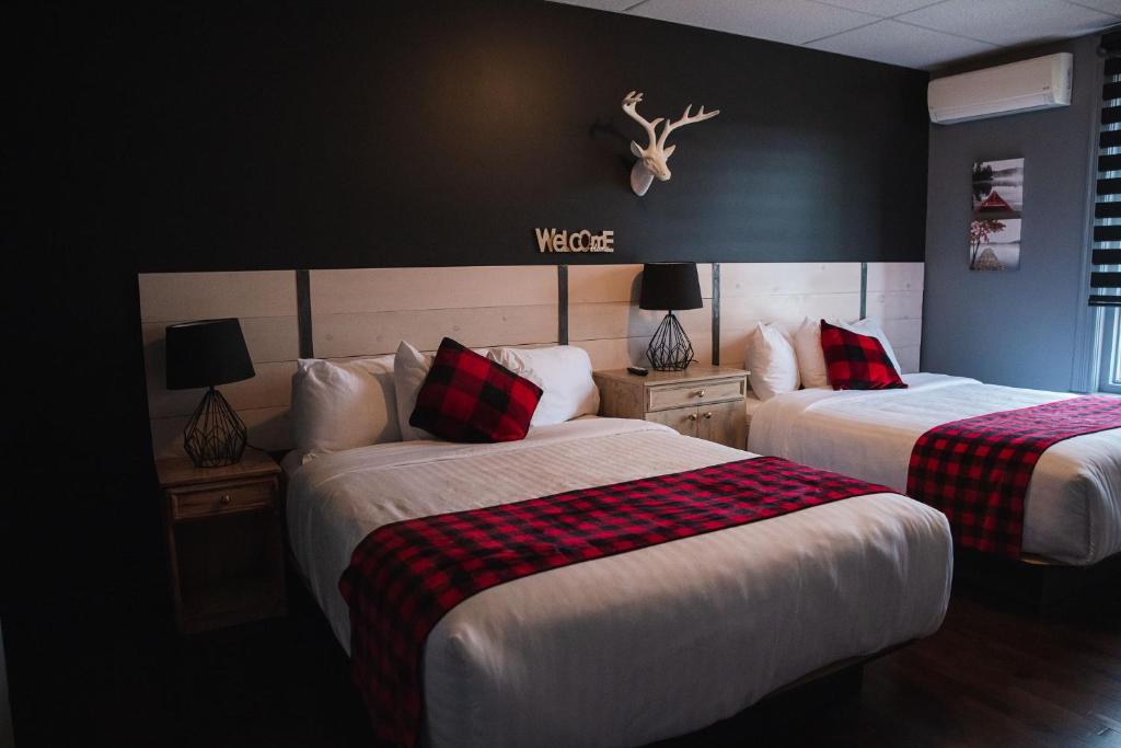 Cette chambre d'hôtel comprend deux lits rouges et noirs. dans l'établissement Auberge Beausejour, à Amqui