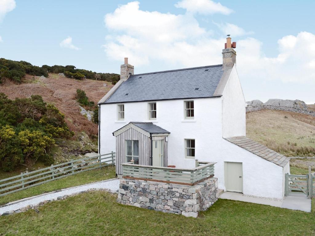 una casa blanca al lado de una colina en The Cottage en Rispond