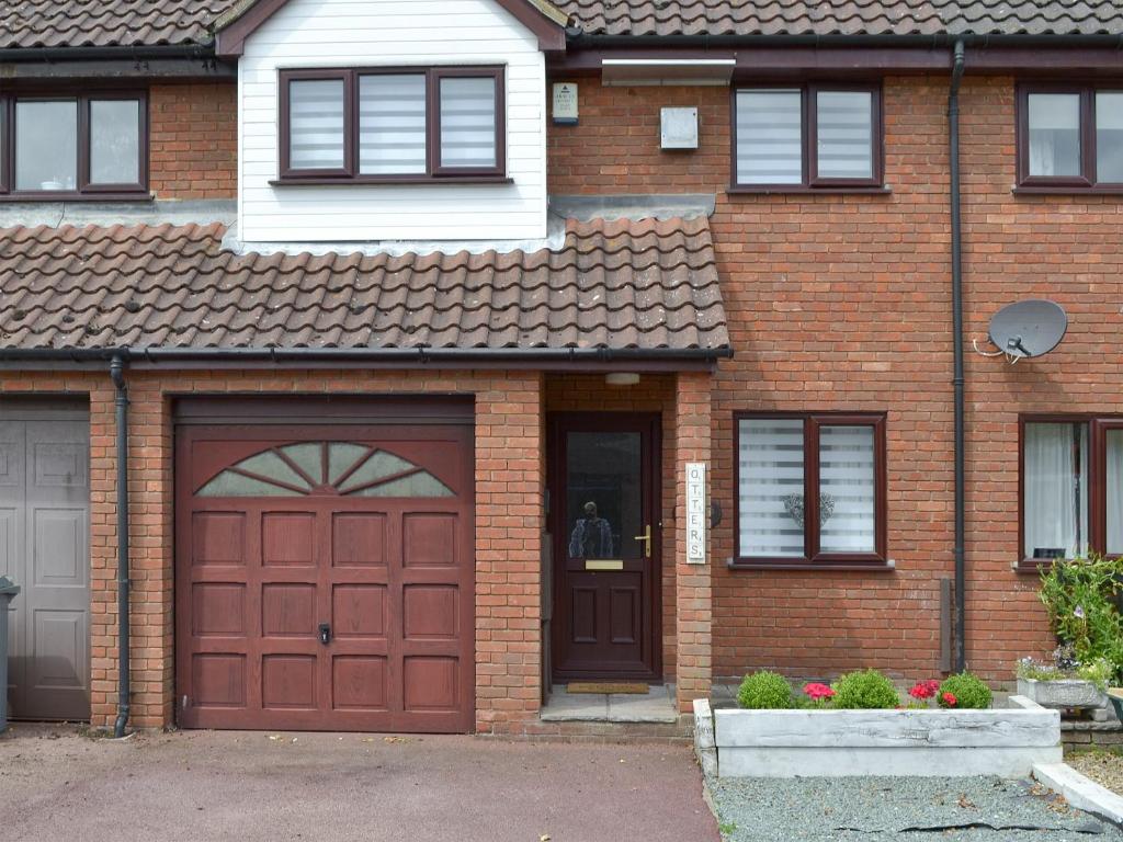 a brick house with a red garage door at Otters in Wroxham