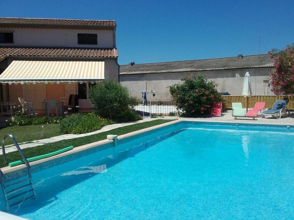 une grande piscine bleue avec deux chaises et une maison dans l'établissement Le gite le goeland a 5 km de la mer, à Fréjus