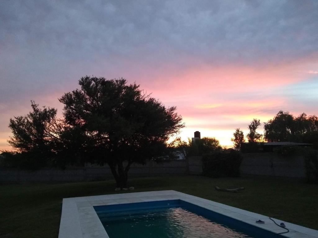 una piscina en un patio con un árbol y una puesta de sol en Quebracho blanco en Bialet Massé