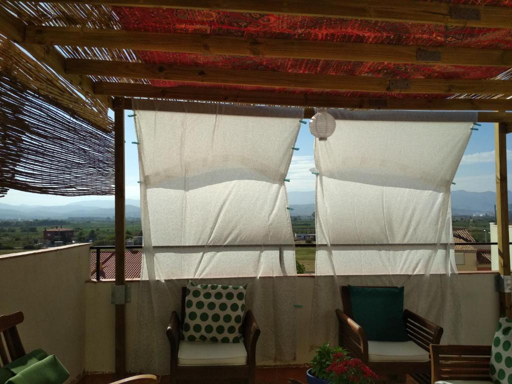a porch with two chairs and two white curtains at Apartamento Cerezo Beach in Xilxes