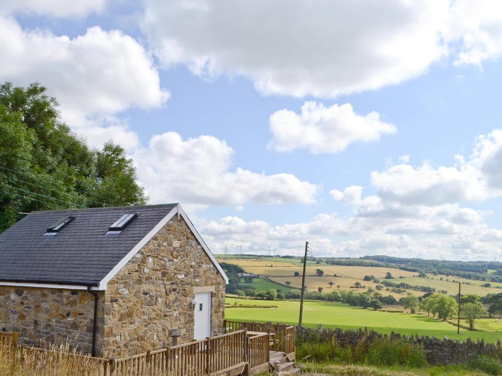 a stone barn with a fence in front of a field at Chestnut Cottage in Knitsley