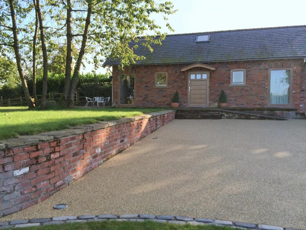 a brick house with a driveway and a brick wall at Red House Farm Cottage in Whitegate