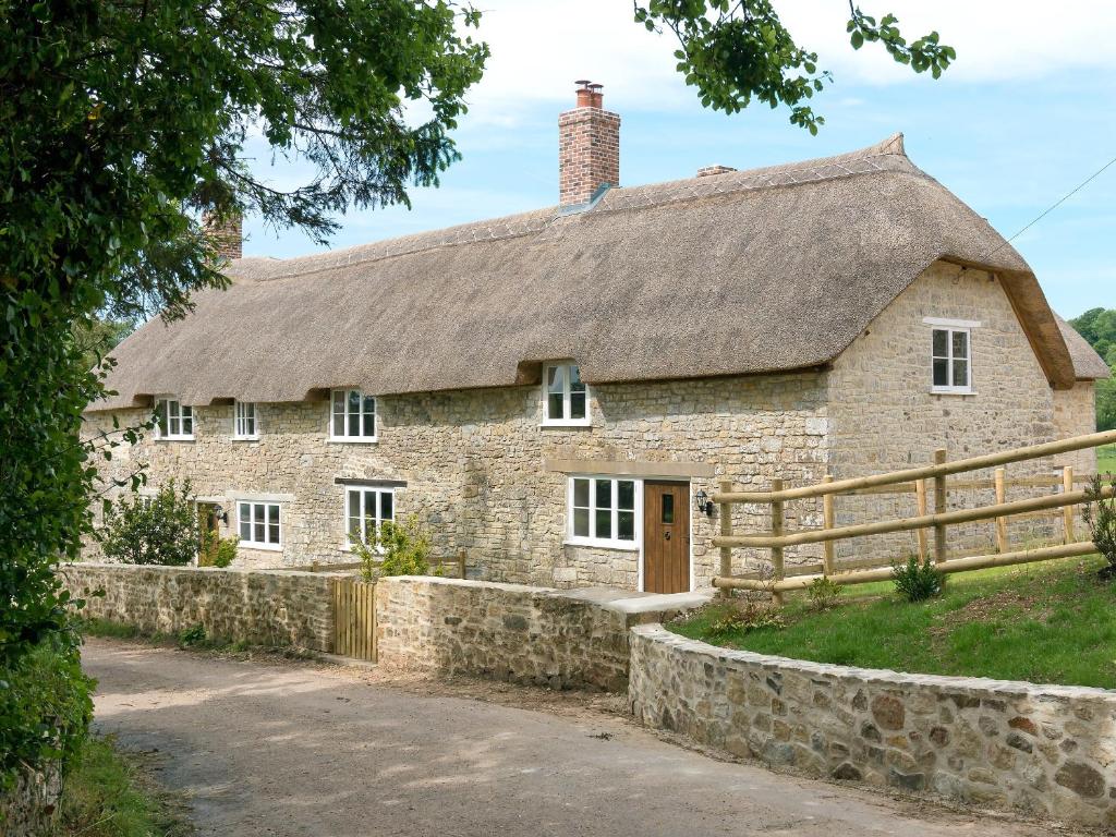 an old stone house with a thatched roof at The Farmhouse At Higher Westwater in Axminster