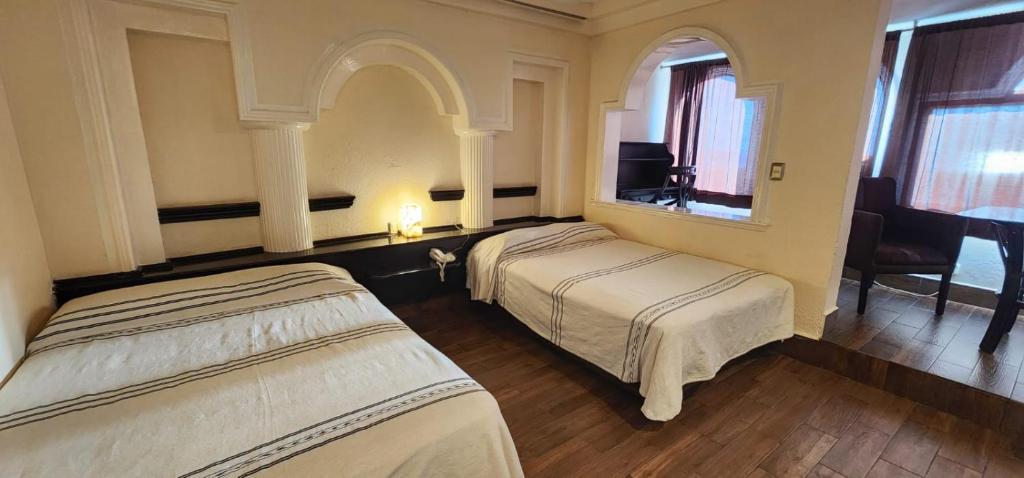 Habitación de hotel con 2 camas y escritorio en Hotel y Restaurant Puesta del Sol en Ocotlán