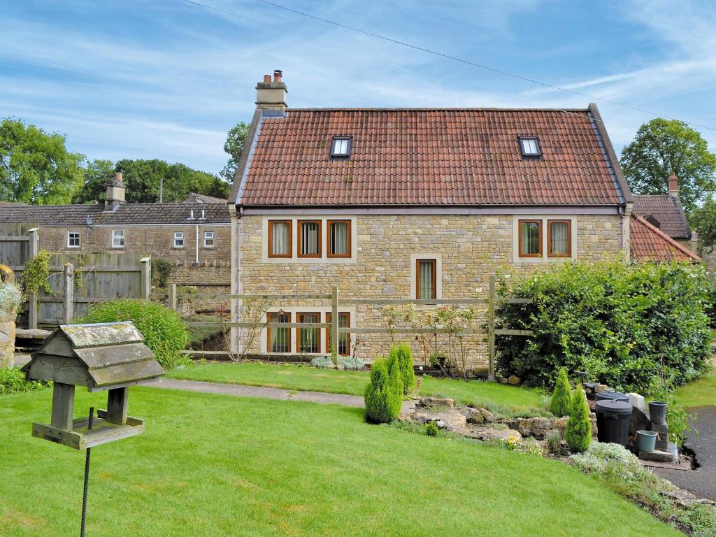 a large brick house with a bird feeder in a yard at The Wagon House in Wellow