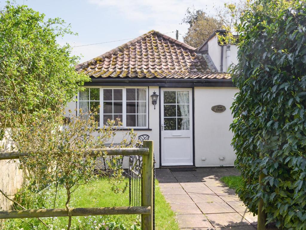 Ce cottage dispose d'une porte blanche et d'une clôture. dans l'établissement Rose Cottage - B6009, à Wendling