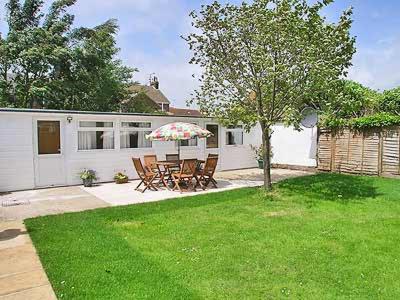 a patio with a table with an umbrella in a yard at Woodlands Lodge in Rustington