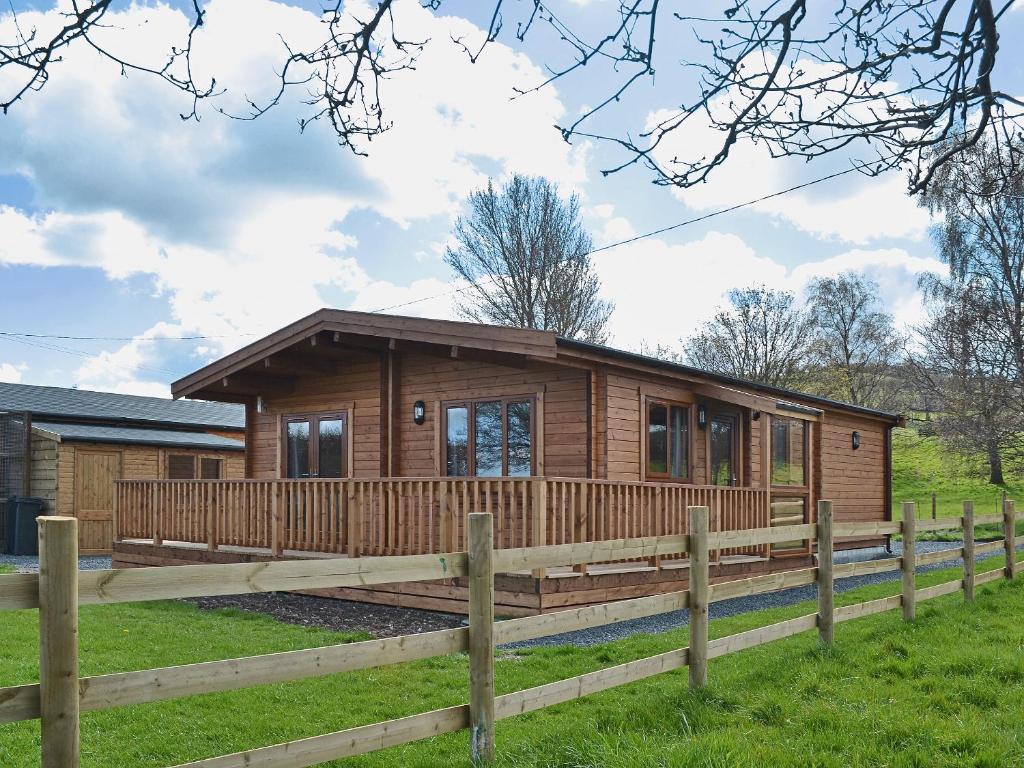 a log cabin in a field with a fence at Callow Lodge in Meadowtown