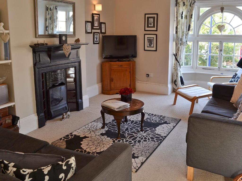 a living room with a fireplace and a tv at The Broomes in Whitstable