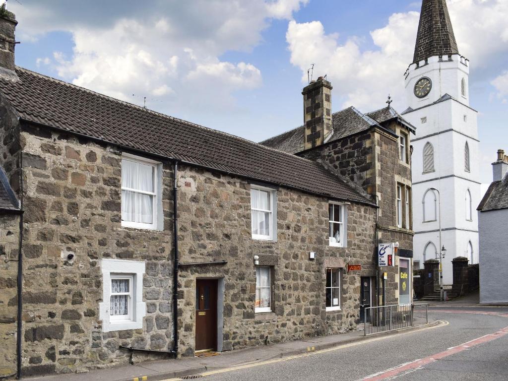 an old stone building with a clock tower on a street at Caroch Cottage in Comrie