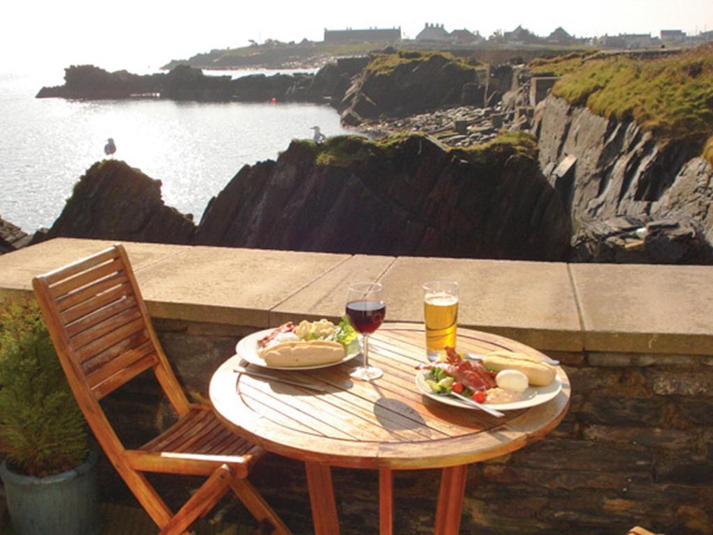 a table with two plates of food and a glass of wine at Old Brewery Cottage - S4576 in Ellanbeich