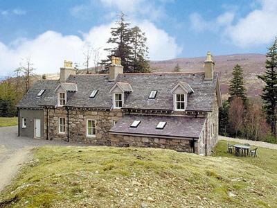 an old stone house sitting on a grassy hill at Mar House in Braemar