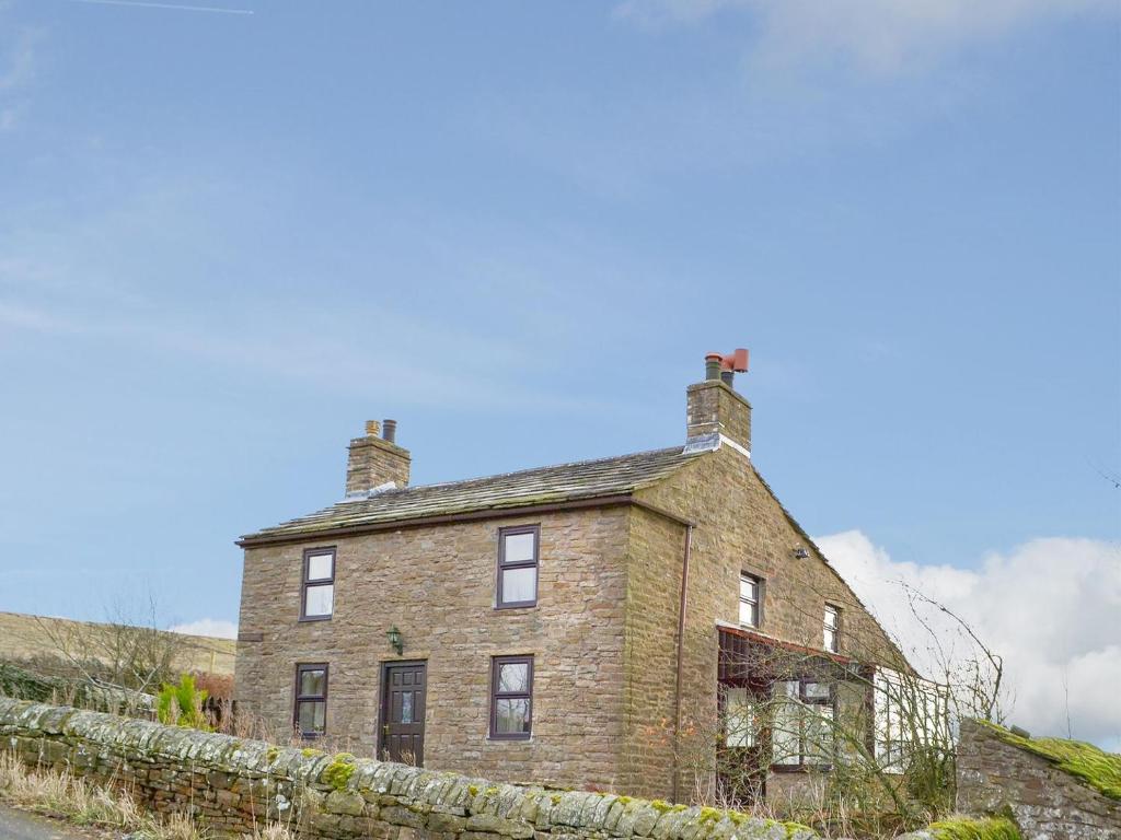 an old brick house on the side of a road at High Windy Cottage in Garrigill