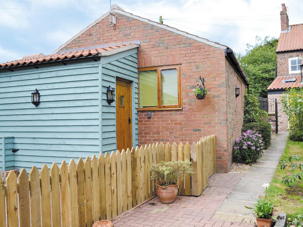 a small blue house with a wooden fence at Garden Cottage in Bridlington