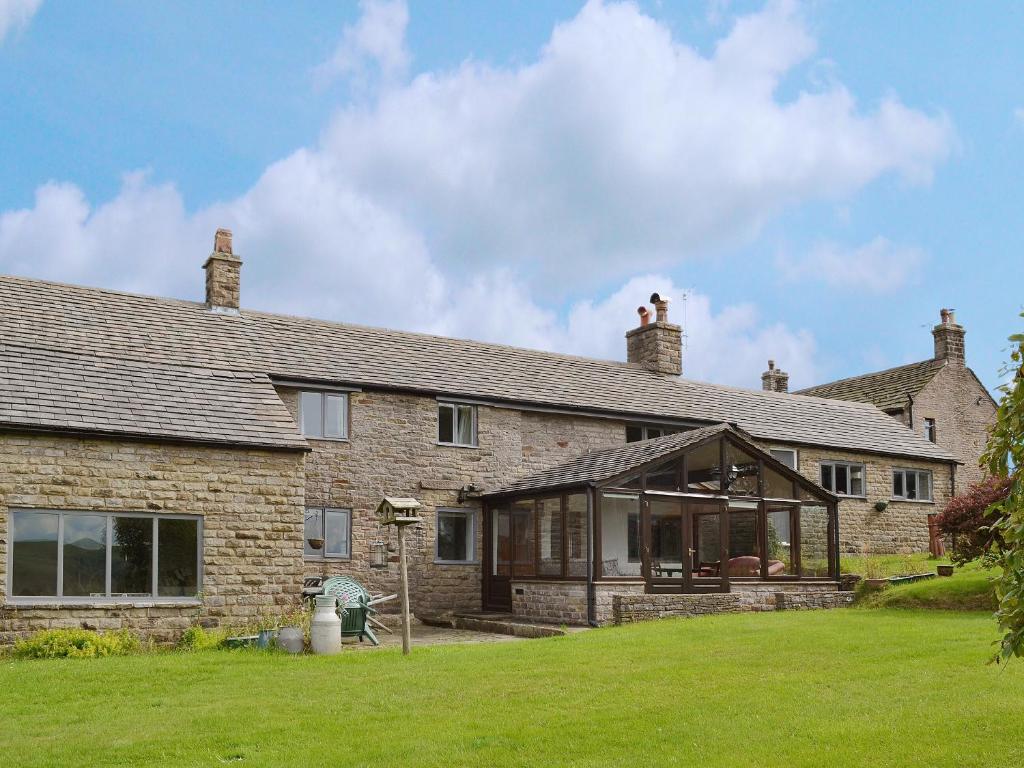 an old brick house with a conservatory on a lawn at Blackhill Gate Cottage in Taxal