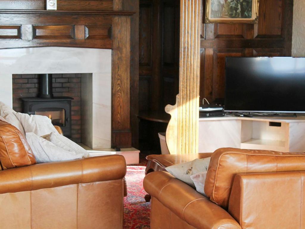 uma sala de estar com um sofá, uma televisão e uma lareira em Maes Y Wawr em Trostre