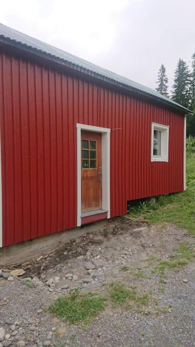 um edifício vermelho com uma porta e uma janela em Nyrenoverad charmig gäststuga med sovloft i Järpen em Järpen