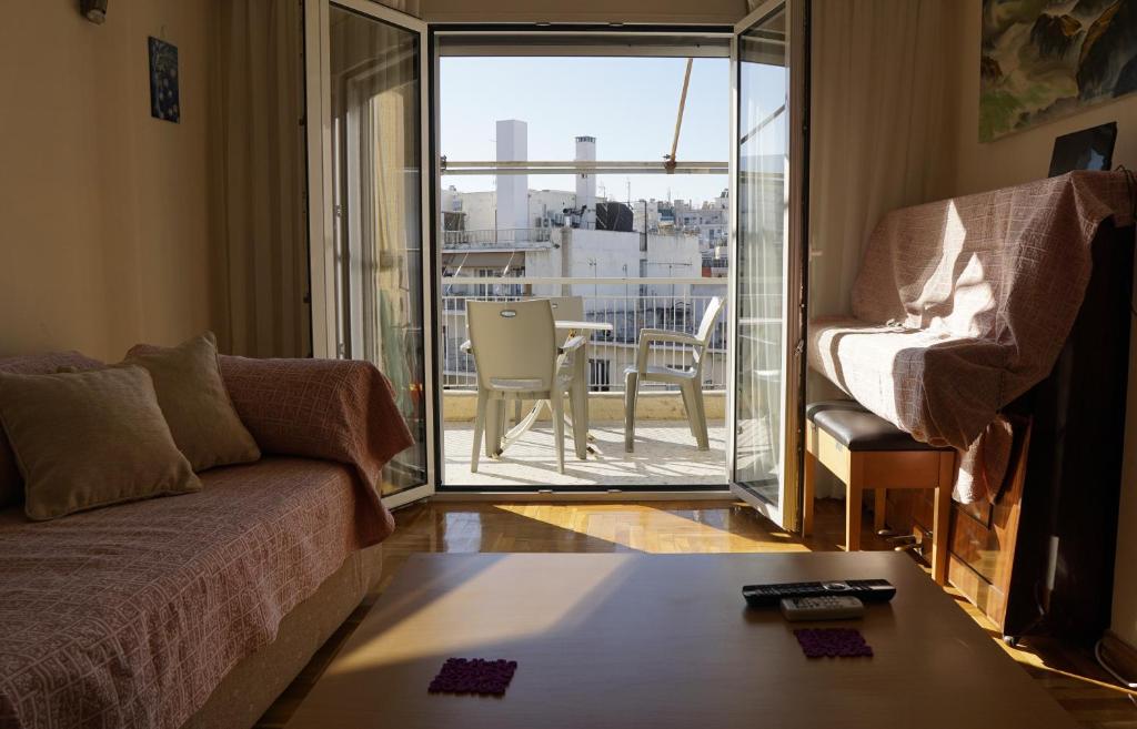 ein Wohnzimmer mit Sofa und Blick auf einen Balkon in der Unterkunft Όμορφο διαμέρισμα ρετιρέ 5ου ορόφου, στου Zografou in Athen