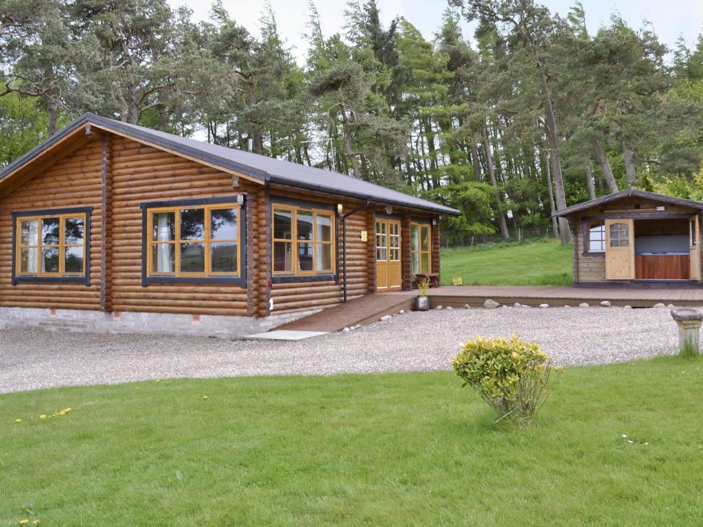 a log cabin with a yard and a house at Ashknowe Log Cabin - S4590 in Glenfarg