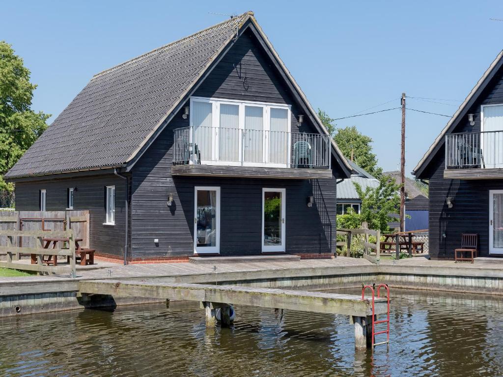 a black house on the water with a dock at Puddle Inn Duck in Horning