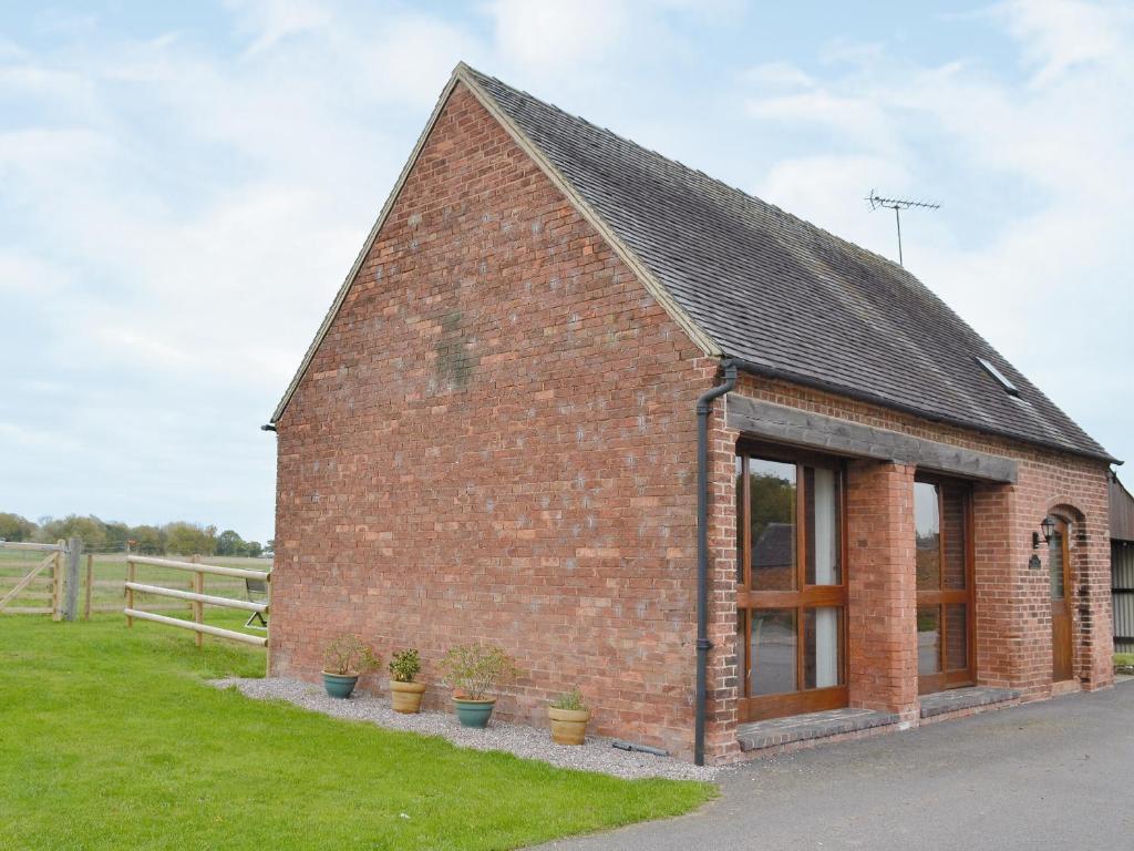 un pequeño edificio de ladrillo con macetas en The Old Carthouse, en Abbots Bromley