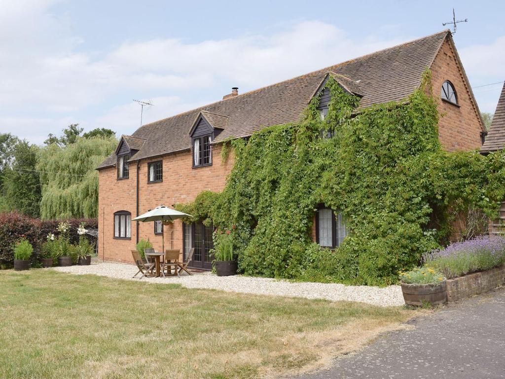 a building covered in ivy with a table and chairs at Mill Cottage in Mathon