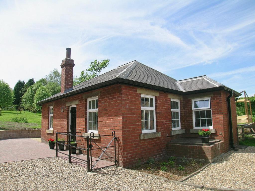 a small brick house with a porch at The Old Pumphouse in Thropton
