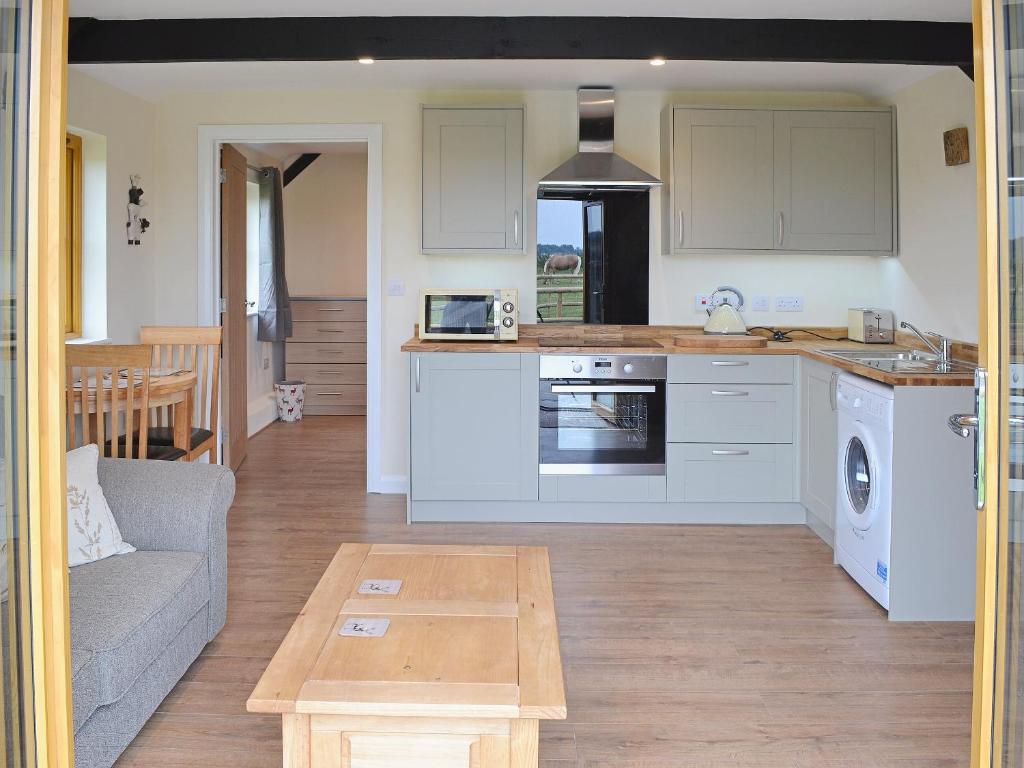 een keuken en een woonkamer met een bank en een tafel bij Saddlers Cottage in Alkham