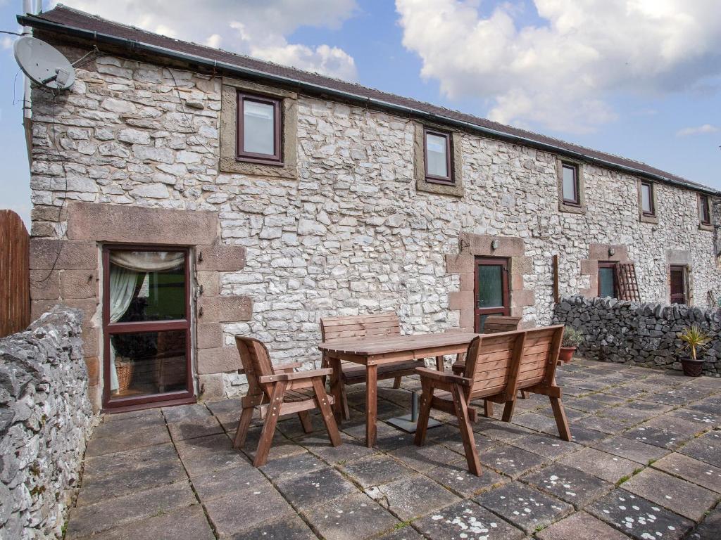 a wooden table and chairs in front of a stone building at Honeysuckle Cottage - 27880 in Elton