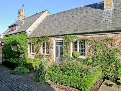 an old brick house with ivy growing on it at Netherall Manor Lodge in Soham