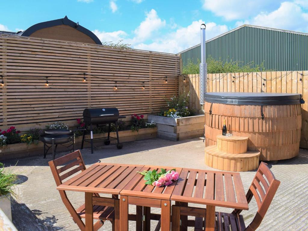 un patio con una mesa de madera con flores. en The Nest - Uk32352, en Ellingham